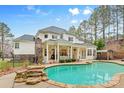 Luxurious backyard featuring a large pool, covered patio, and meticulously landscaped surroundings at 133 Crooked Branch Way, Troutman, NC 28166