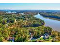 Expansive aerial view of a lakeside property showcasing a house surrounded by trees, with lake access at 1547 Sunset Pointe Dr, Salisbury, NC 28146