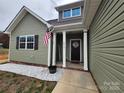 Inviting home with olive siding, covered porch, white columns, and American flag at 4017 Avis Way, Monroe, NC 28110