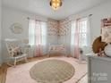 Charming Bedroom with soft pink accents, a rocking chair, and a cozy crib at 5622 S Rocky River Rd, Monroe, NC 28112