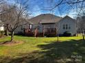 Spacious backyard featuring a wooden deck, green grass, and a charming exterior at 7700 Sedgebrook E Dr, Stanley, NC 28164