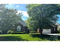 Inviting brick home showcases manicured landscaping and attached garage, nestled among mature trees at 7700 Sedgebrook E Dr, Stanley, NC 28164