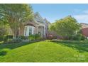 Beautifully landscaped front yard with lush green lawn and mature trees surrounding the brick home at 820 Hampshire Hill Rd # 106, Matthews, NC 28105