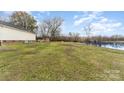 View of the back exterior with lake access, and a spacious yard with mature trees at 24697 Ramsey Dr, Albemarle, NC 28001