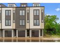New townhome with a modern design, featuring mixed siding, a black garage door, and ample natural light at 3206 Riley Ave, Charlotte, NC 28269