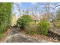 Scenic exterior shot of a quaint home nestled amongst lush greenery, featuring a driveway and carport in a wooded area at 335 Summit Se Ct, Concord, NC 28025