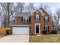 Charming two-story brick home with a well-manicured lawn, attached garage and a black front door at 10211 Ridgewell Ct, Charlotte, NC 28215