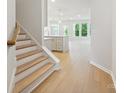 Entryway with wood floors, white trim, a staircase, and a glimpse into the open-concept kitchen and living area at 113 Alluvium Ln, Waxhaw, NC 28173