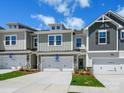 A row of new townhomes showcases varied exterior colors, stone accents, and white garages on a sunny day at 113 Alluvium Ln, Waxhaw, NC 28173