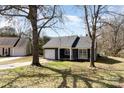 Charming one-story home with a single-car garage, dark siding, and mature trees in the yard at 12319 Delcorte Ln, Pineville, NC 28134