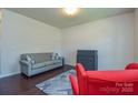 Cozy living room showcasing a gray sofa, red armchair, dark floors, and a neutral-toned rug at 173 Glastonbury Dr, Mooresville, NC 28115