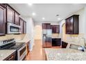 Modern kitchen with stainless steel appliances, granite countertops, and dark wood cabinets at 2679 Southern Trace Dr, Waxhaw, NC 28173