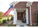 Inviting brick front porch with rocking chairs and American flag creates a warm and welcoming entrance to the home at 3089 Founding Fathers Dr # 43, Gastonia, NC 28056