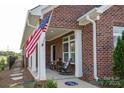 Inviting brick front porch with rocking chairs and American flag creates a warm and welcoming entrance to the home at 3089 Founding Fathers Dr # 43, Gastonia, NC 28056