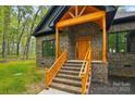 Inviting brick home entrance with a prominent wood porch featuring matching wood railing and a striking front door at 3738 Glen Arbor Dr, Maiden, NC 28650