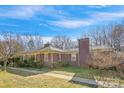 Low angle showcasing a single-story red brick home with a chimney and tidy landscaping at 3901 Starmount Ave, Charlotte, NC 28269