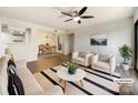 Bright, staged living room with hardwood floors, ceiling fan, sofa, armchairs, striped rug, and adjacent dining area at 4918 Sardis Rd # E, Charlotte, NC 28270