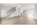 Open-concept living area featuring hardwood floors, a staircase, modern lighting, and a view of the bright kitchen at 6535 Fisher Farm Nw Ln, Concord, NC 28027