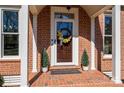 Inviting front entrance with a decorative wreath, potted plants, and a welcoming doormat on a brick porch at 1336 College Ave, Shelby, NC 28152