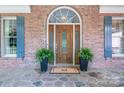 Elegant front entrance featuring a decorative wooden door, sidelights, transom window, and potted plants at 13822 Tributary Ct, Davidson, NC 28036