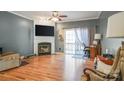 Bright living room featuring a cozy fireplace, hardwood floors, and sliding glass doors to a deck at 2864 Sweeping Pine Ln, Denver, NC 28037