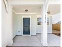 Close-up of front porch featuring stylish lighting, white columns, a modern dark blue door, and the house number at 3215 Isenhour St, Charlotte, NC 28206