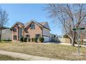 View of the brick home on a corner lot, with a three-car garage and a wooden fence at 5000 Tulip Ln, Matthews, NC 28104