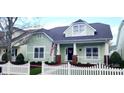 Charming light green two-story home with white picket fence, American flag, and inviting front porch at 7037 Ladys Secret Dr, Indian Trail, NC 28079