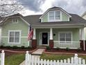 Inviting green home with a cozy front porch, red brick accents and a well-maintained front yard at 7037 Ladys Secret Dr, Indian Trail, NC 28079