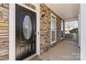 Front door to home with beautiful stonework, an oval window, and traditional hardware at 13014 Windy Lea Ln, Huntersville, NC 28078
