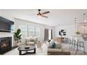 Bright living room featuring a fireplace, ceiling fan, large windows, and an open floor plan leading to the kitchen at 15119 Oleander Dr, Charlotte, NC 28278