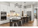 Modern kitchen with stainless steel appliances, white cabinetry, a large island with barstool seating, and stylish pendant lights at 2227 Indigo Branch Rd, Indian Land, SC 29707