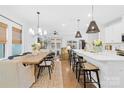 Open-concept dining room and kitchen with hardwood floors and modern lighting fixtures at 3512 Auburn Curb Rd, Charlotte, NC 28217
