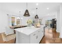 Bright, open kitchen with an island, hardwood floors, gold hardware, and a view of the dining area at 3512 Auburn Curb Rd, Charlotte, NC 28217