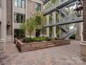 A brick-paved courtyard featuring a steel staircase and manicured trees at 1333 Queens Rd # B1, Charlotte, NC 28207