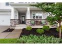 Inviting front porch with stone pillars and seating, surrounded by manicured landscaping at 16725 Cozy Cove Rd, Charlotte, NC 28278