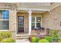 Inviting front porch with brick facade and decorative columns, a charming entrance to the home with seating at 17927 Culross Ln, Charlotte, NC 28278
