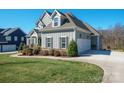 Beautiful home featuring well-manicured lawn, vertical siding, a three-car garage, and a charming landscape at 190 Hidden Meadows Dr, Mooresville, NC 28117