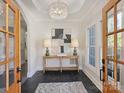 Inviting foyer with black herringbone floors, console table, chandelier, rug and lots of natural light at 2004 Lombardy Cir, Charlotte, NC 28203