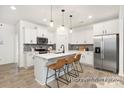 Bright kitchen with white cabinets, stainless steel appliances, large island with seating, and modern pendant lighting at 11327 Magpie Ct # 6, Charlotte, NC 28215