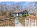 Lovely single-story home with a gray exterior, wooden porch, and white picket fence in a natural setting at 135 Natures Way, Mount Holly, NC 28120