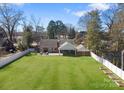 Large, green backyard showcasing a patio area, bordered by a white fence and garden beds at 2701 Sharon Rd, Charlotte, NC 28211