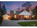 Attractive brick home with well-lit windows, dormers, and a detached garage on a paved driveway at 2701 Sharon Rd, Charlotte, NC 28211