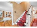 Elegant staircase featuring a red patterned runner, white banister, and classic hardwood flooring at 329 N Oakwood Dr, Statesville, NC 28677
