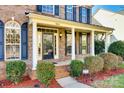 Inviting front porch featuring white columns, brick steps, and manicured landscaping at 8315 Bridgegate Dr, Huntersville, NC 28078