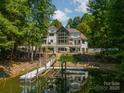 Back of home featuring a boat dock and lake access, surrounded by mature trees and lush greenery at 129 Tuckernuck Dr, Mooresville, NC 28117