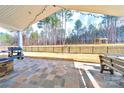 Spacious covered patio with stone flooring, a grill, outdoor seating, and a large fenced backyard with mature trees at 136 Falls Leaf Dr, Troutman, NC 28166