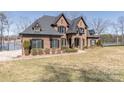 View of home's exterior, showcasing brick facade, black trim, lake view, and landscaping at 5628 Creole Rd, Clover, SC 29710