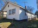 View of home's back exterior featuring an enclosed porch, ample windows and a chain-link fence at 105 Mcgill Nw Ave, Concord, NC 28025