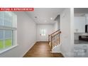 View from kitchen nook into light, bright entryway with wood flooring and staircase at 11217 Cardinal Creek Ave, Charlotte, NC 28215